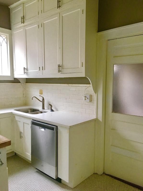 a small kitchen with white cabinets and a dishwasher