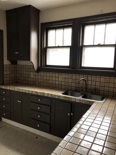 A kitchen with black cabinets and a tiled backsplash.