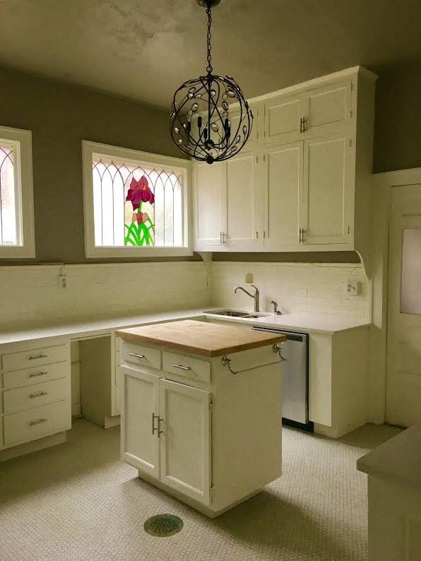 an empty kitchen with white cabinets and a sink