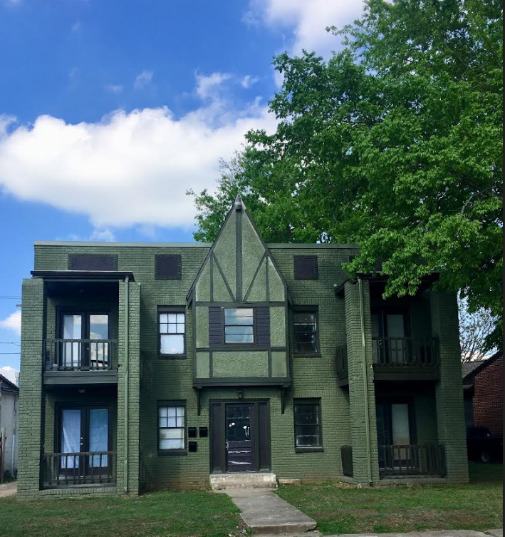 a green building with a tree in front of it
