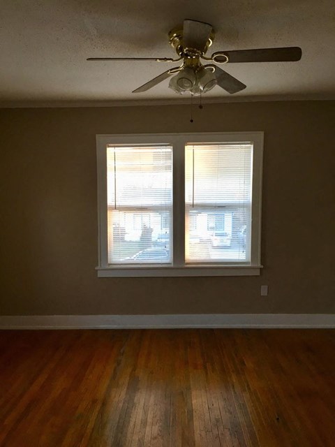a living room with a ceiling fan and two windows