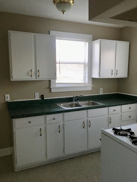 a kitchen with white cabinets and a sink and a window