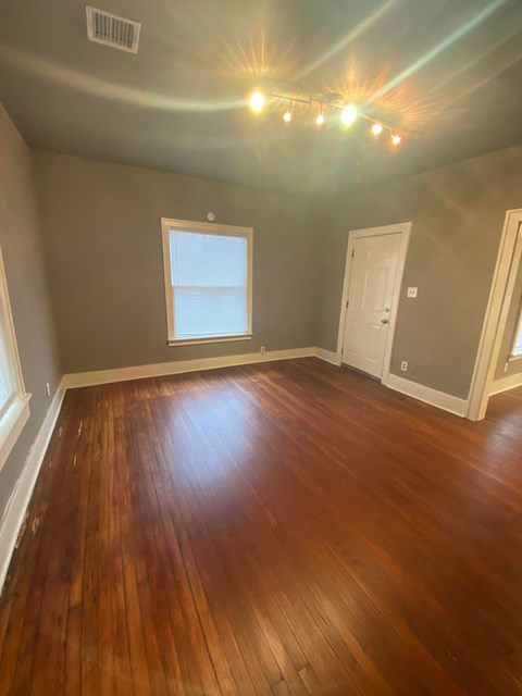 an empty living room with wooden floors and a window