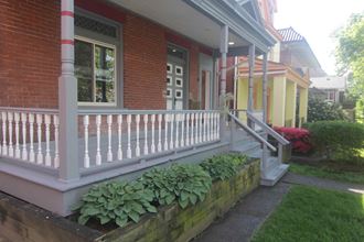 a porch with a white railing and plants on it