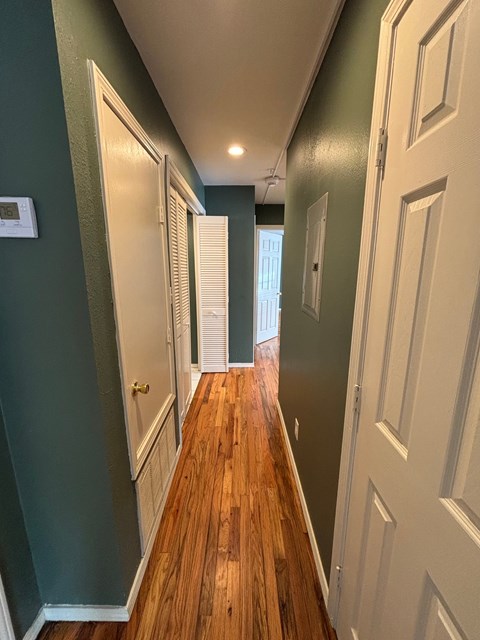 A long hallway with white doors and green walls.