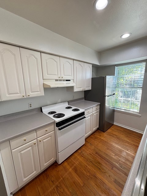 A kitchen with white cabinets and a black refrigerator.