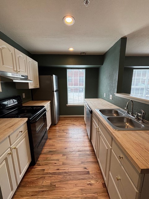 A kitchen with wooden floors and white cabinets.