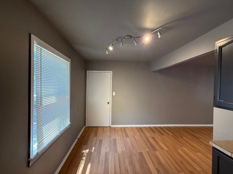 A room with wooden flooring and a window with blinds.