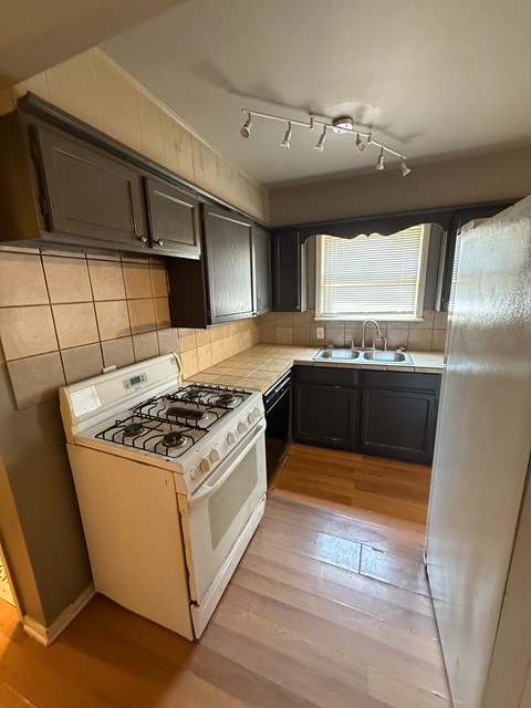 A kitchen with a white stove and black cabinets.