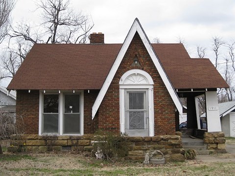 A small brick house with a white door and a porch.