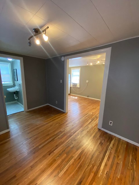 an empty living room with a hard wood floor and a ceiling fan