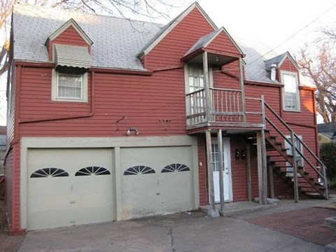 a red house with two garage doors and a staircase