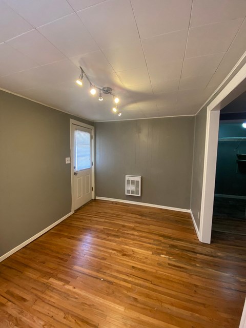 a living room with wood floors and grey walls and a window