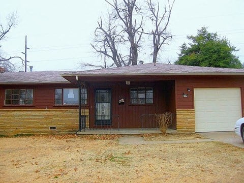 A brown house with a white garage door and a black door.