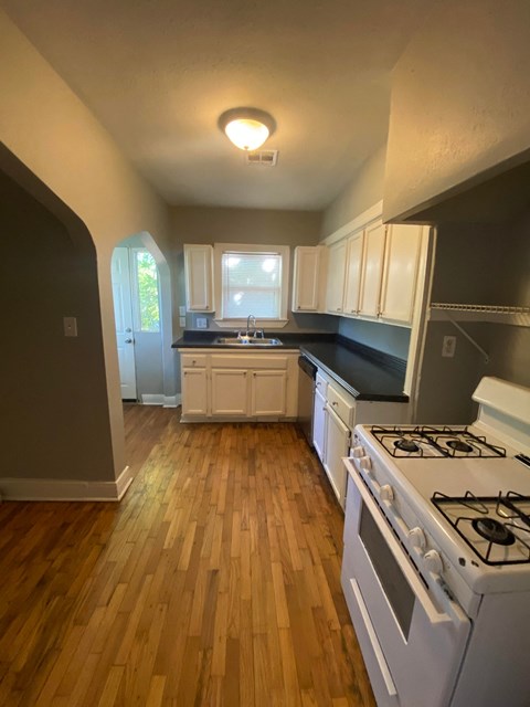 a kitchen with a stove and a wooden floor