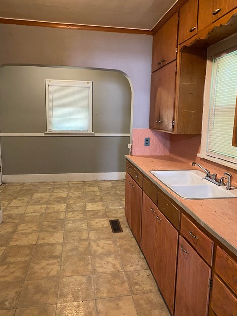 an empty kitchen with wooden cabinets and a sink