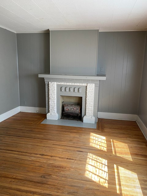 an empty living room with a fireplace and wooden floors