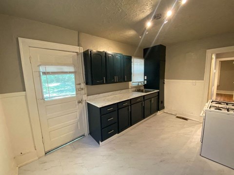 an empty kitchen with black cabinets and a door