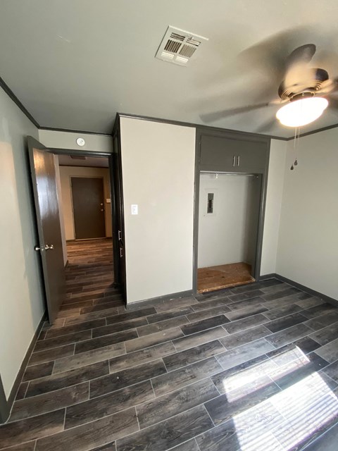 an empty living room with a wood floor and a ceiling fan