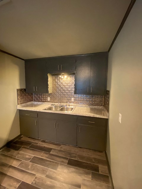 an empty kitchen with dark cabinets and a sink