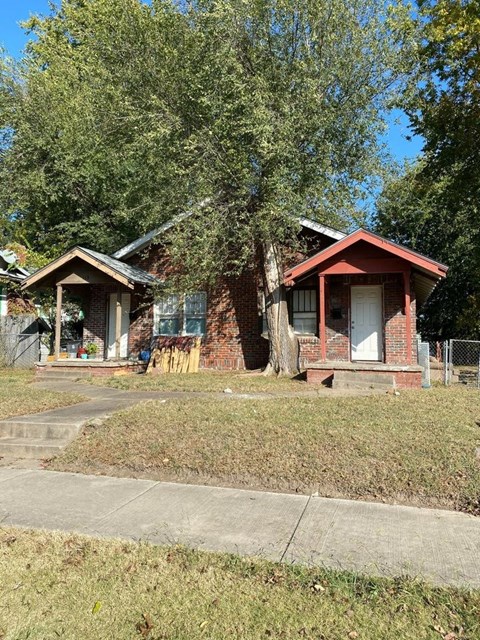 a small brick house with a sidewalk in front of it
