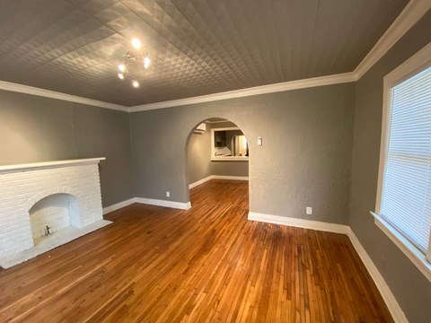 an empty living room with a fireplace and wooden floors