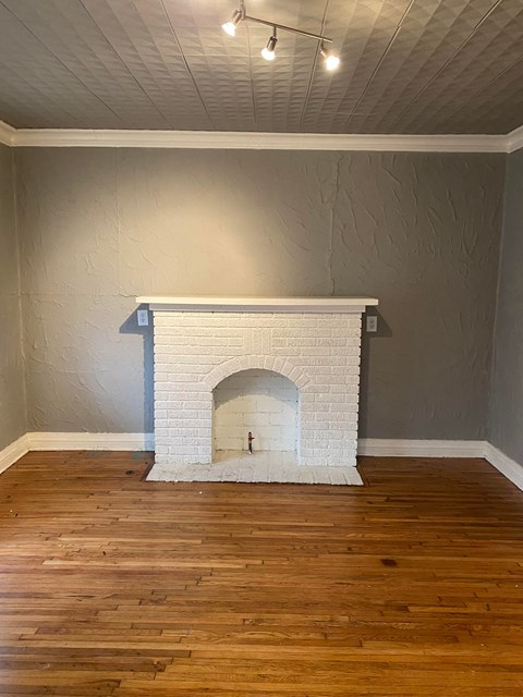 the living room has a brick fireplace and wooden floors