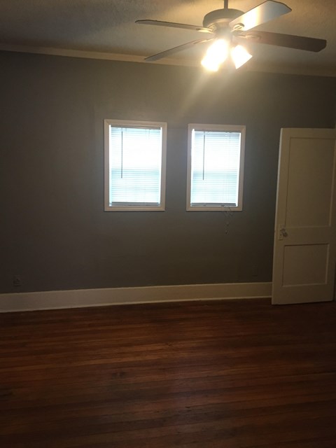 a living room with a ceiling fan and two windows