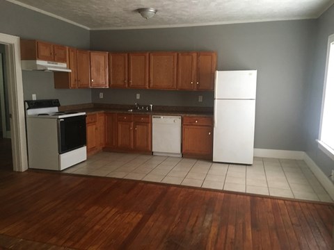 an empty kitchen with wooden cabinets and white appliances