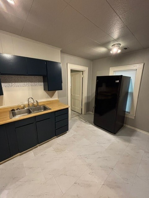 A kitchen with black cabinets and a black refrigerator.