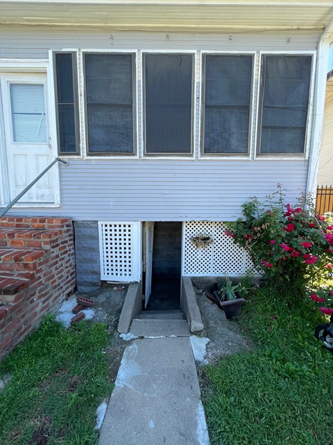 A small doorway in a house with a brick wall and a window above it.