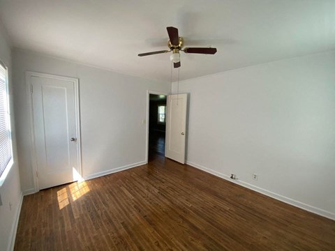 an empty living room with wood floors and a ceiling fan