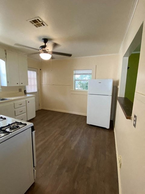 a kitchen with a refrigerator and a stove and a ceiling fan