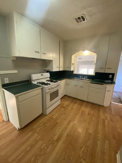 an empty kitchen with white appliances and white cabinets