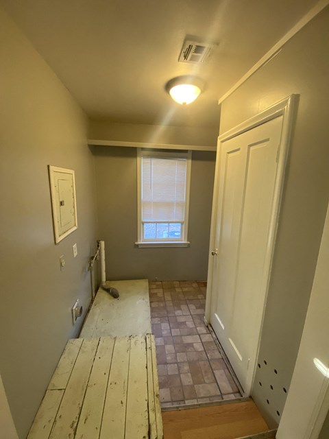 a view from the top of the stairs looking down the hallway with the door open