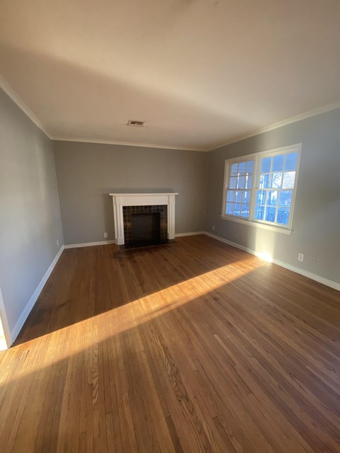 an empty living room with wooden floors and a fireplace