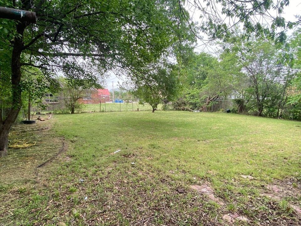 a grassy field with trees and a fence