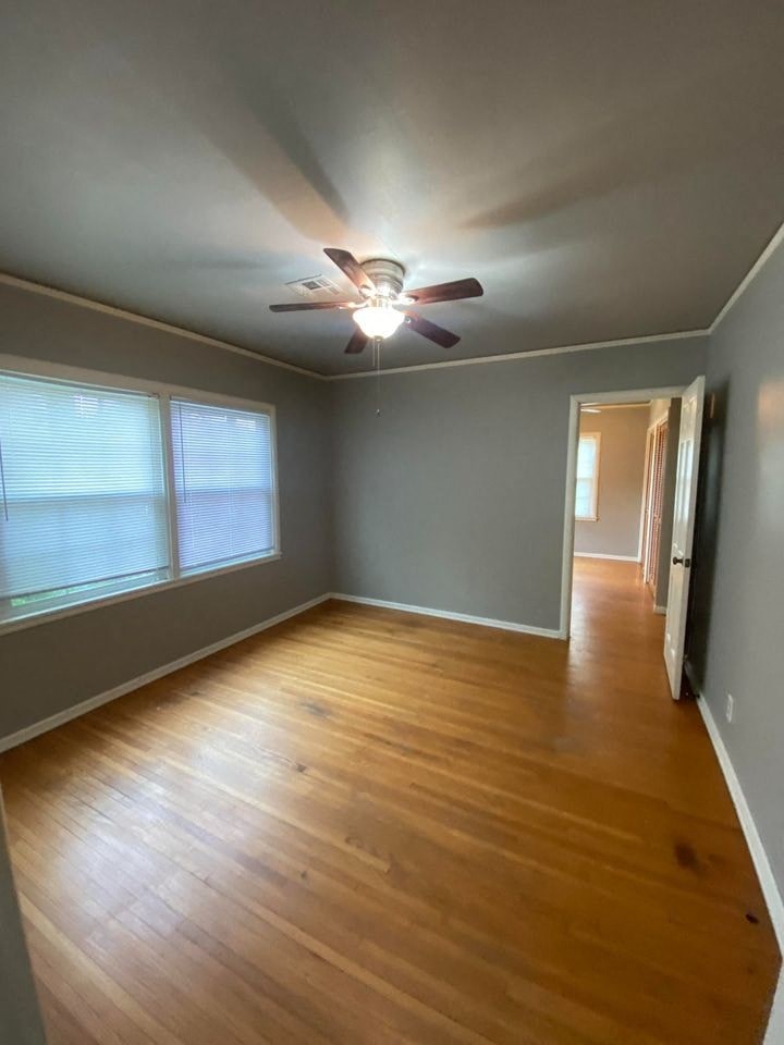 an empty living room with a ceiling fan and wood floors