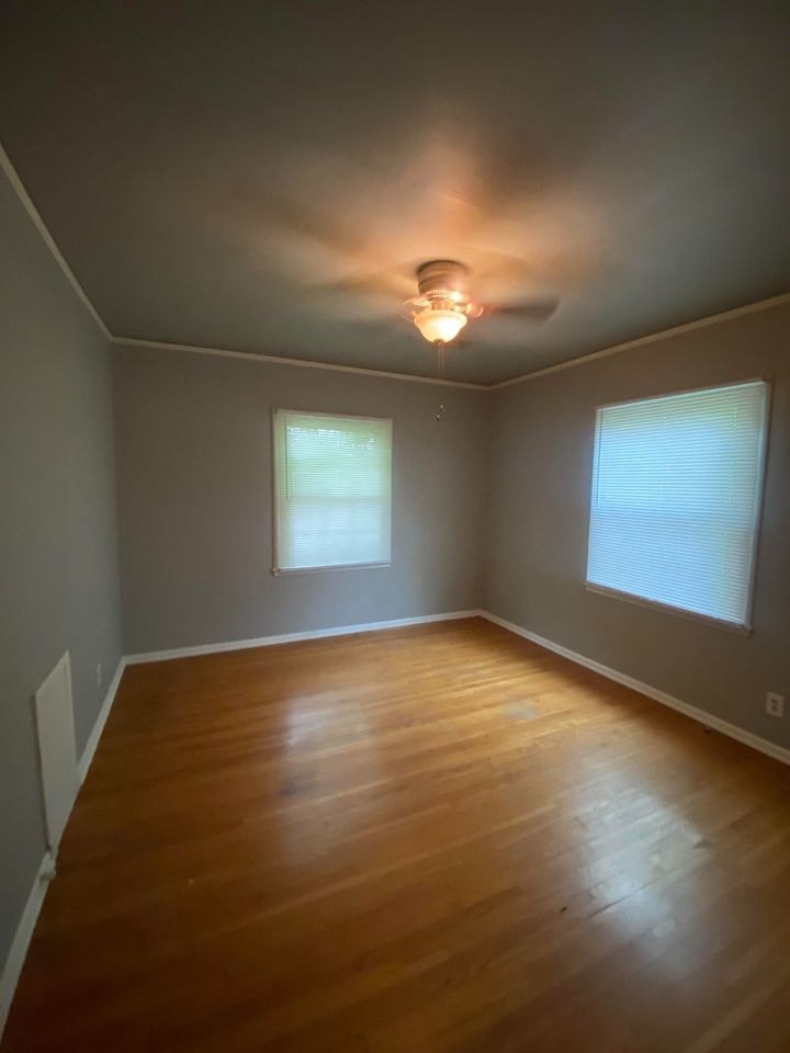 an empty room with a wood floor and a ceiling fan