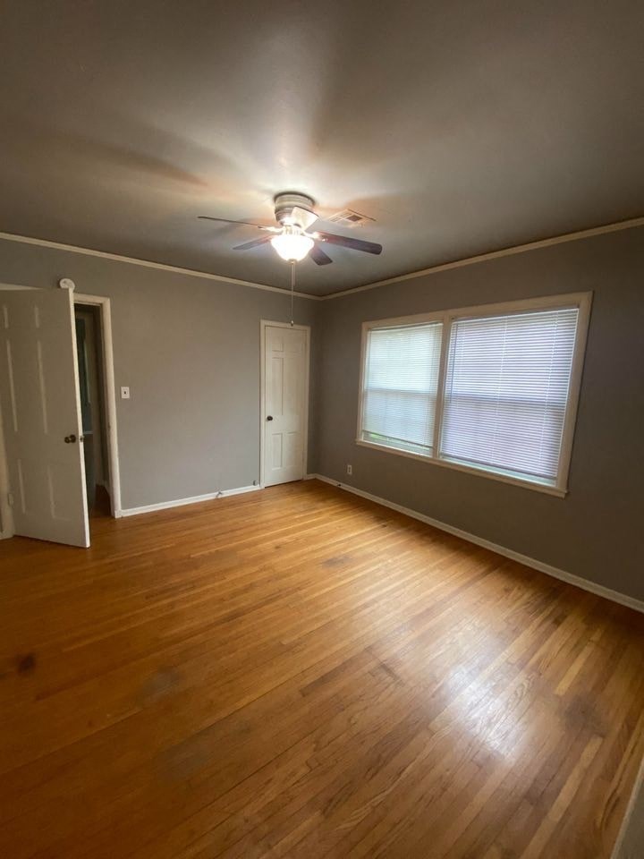 an empty living room with a ceiling fan and a window