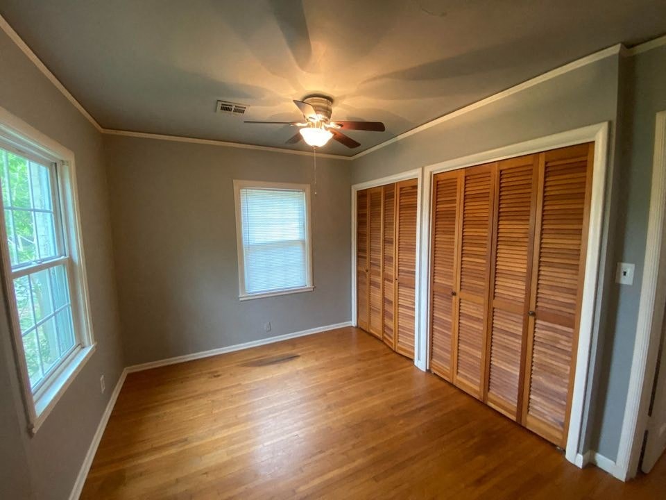 a empty living room with a ceiling fan and a closet