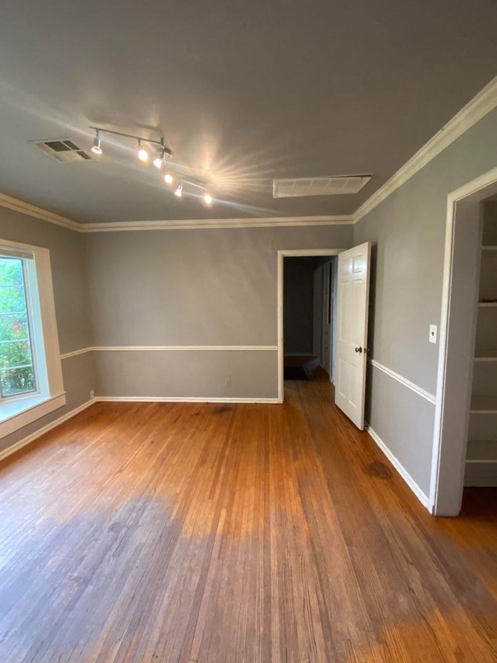 an empty living room with wood flooring and gray walls