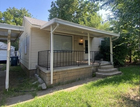 A small house with a porch and a black railing.