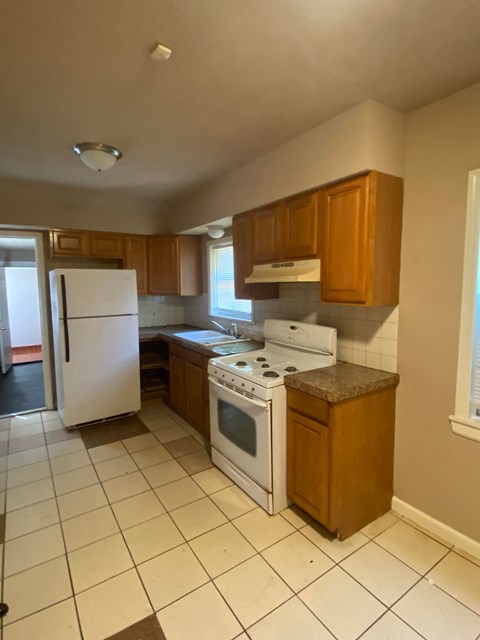 an empty kitchen with white appliances and wooden cabinets