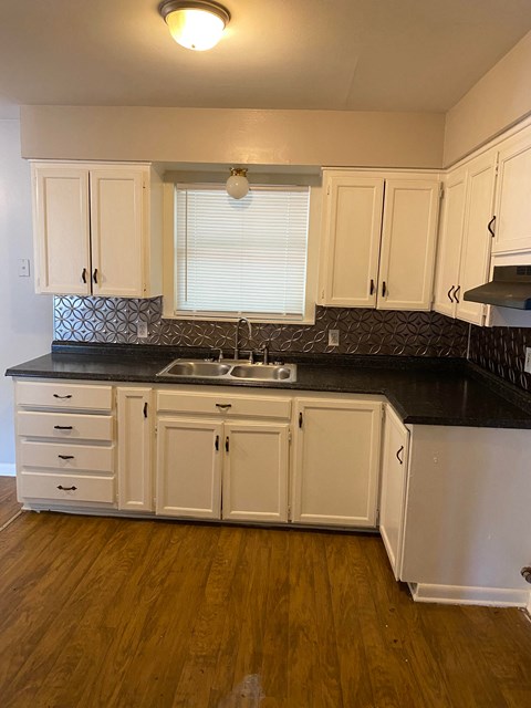 a kitchen with white cabinets and a black counter top