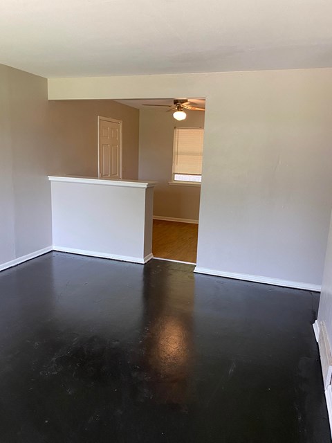 an empty living room with white walls and a black floor