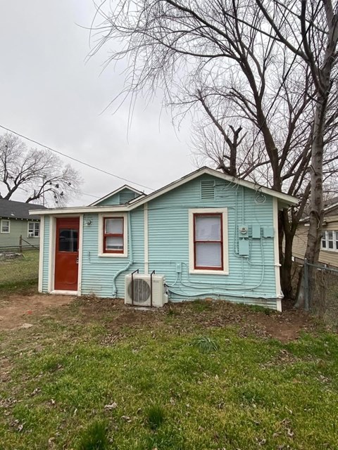 A blue house with a red door and two air conditioning units.