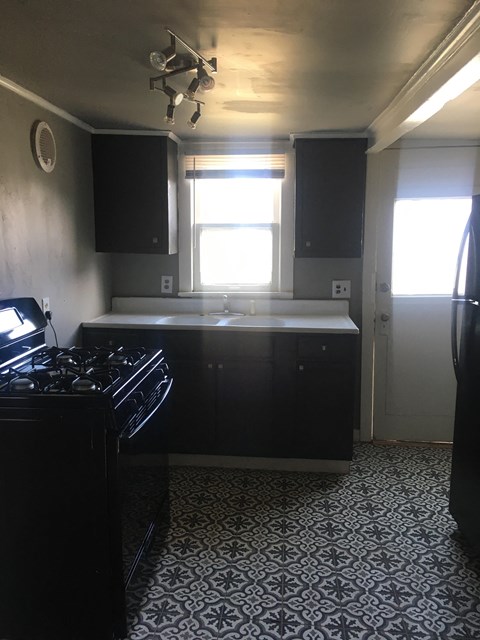 A kitchen with black cabinets and a patterned floor.