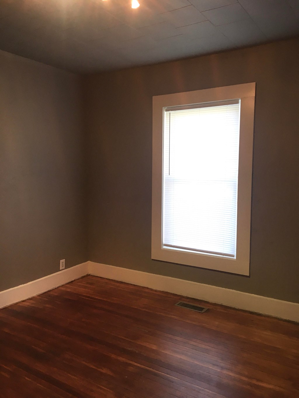 an empty room with a window and wooden floors