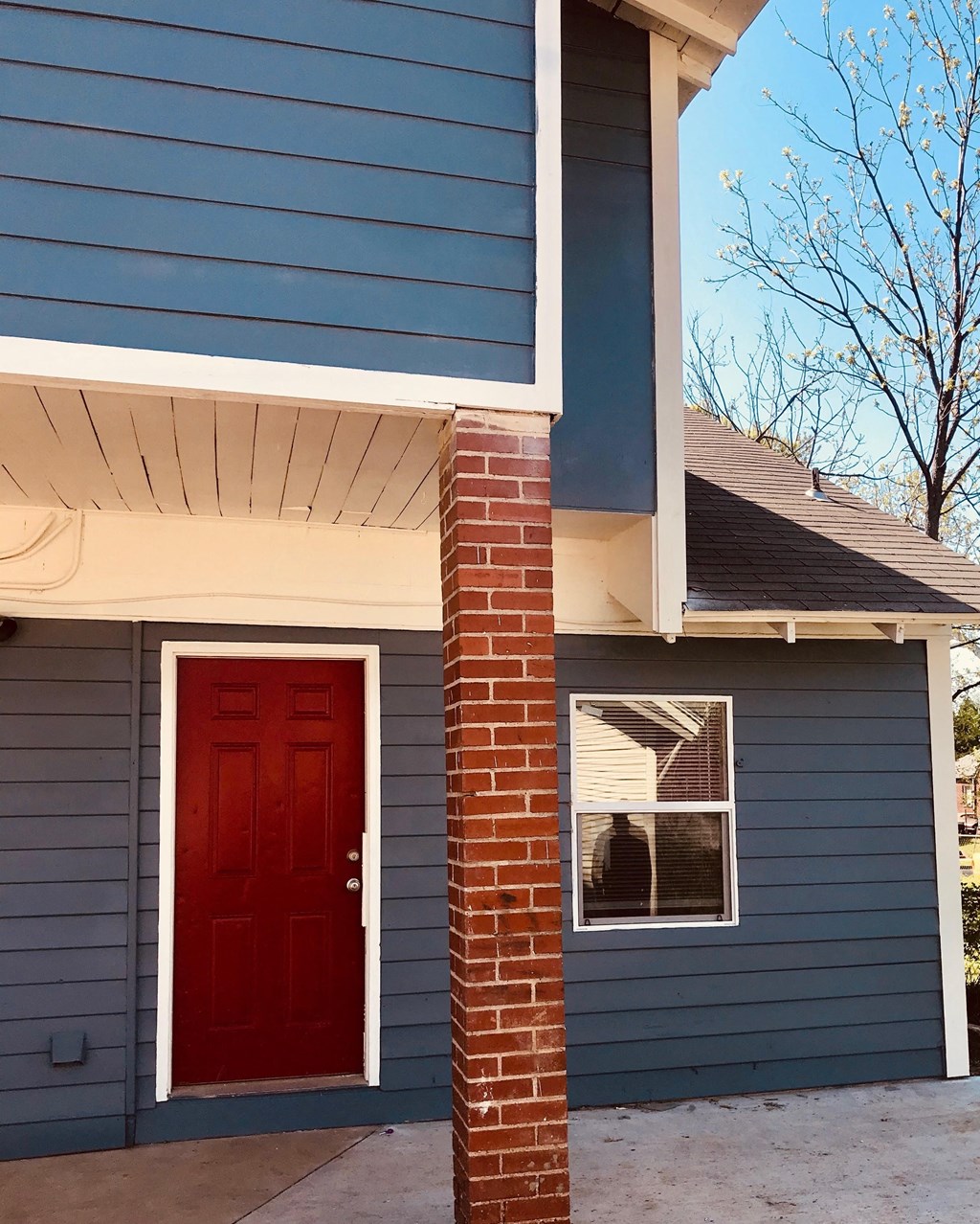 a red door on a blue house with a brick pillar